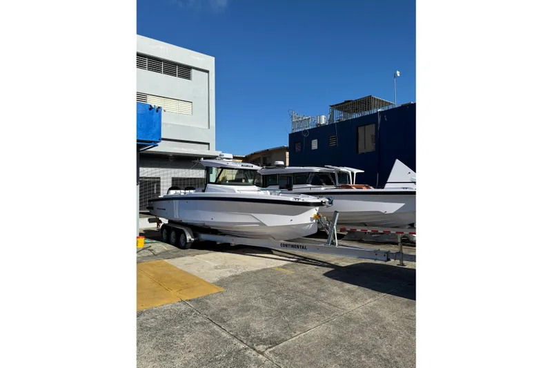 Slide: The Image of 2025 Axopar 29 CCX boat on trailer, parked outdoors under clear blue sky. - 2
