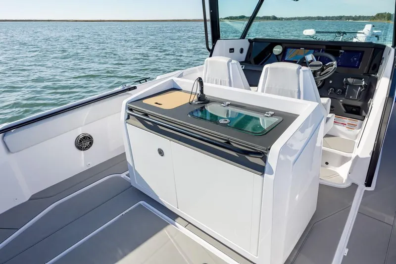 Slide: The Image of 2025 Axopar 29 CCX boat interior with sink and seating, on calm water. - 4