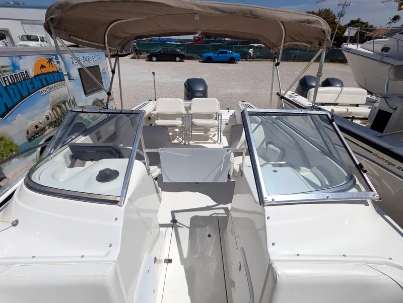 Slide: The Image of 2003 Wellcraft 210 Sportsman boat with dual consoles and canopy in a marina setting. - 10