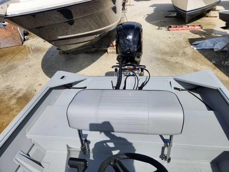 Slide: The Image of 2025 SeaArk 1872 MVT boat interior with motor and seating, parked outdoors. - 5