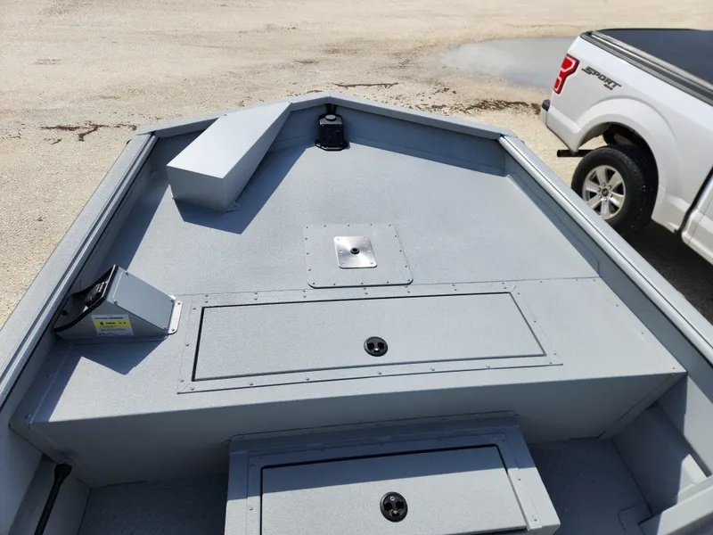 Slide: The Image of 2025 SeaArk 1872 MVT boat interior with storage compartments, parked near a white truck. - 6