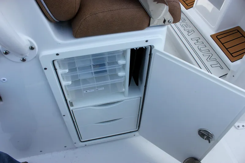 Slide: The Image of 2025 Sea Hunt Gamefish 28 storage compartment with open door and tackle boxes. - 32