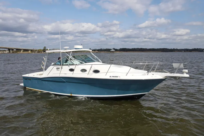 The Image of 2004 Wellcraft 330 Coastal boat cruising on a calm lake under a cloudy sky. - 0