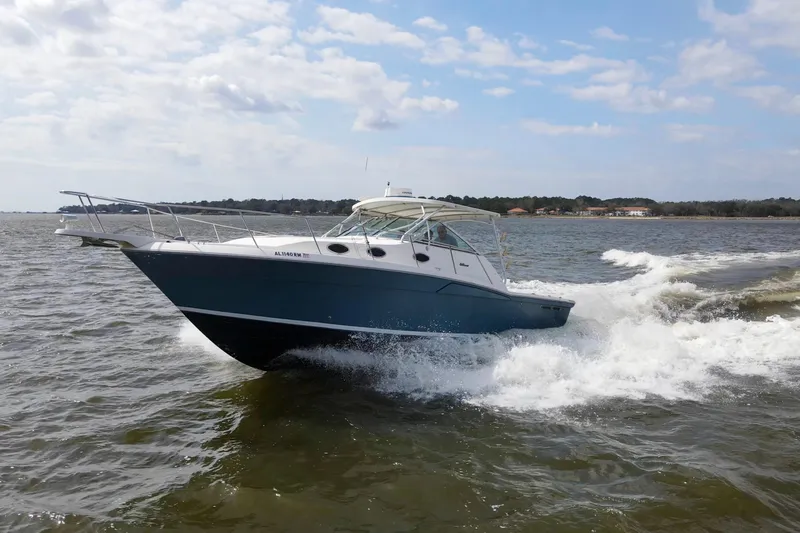 Slide: The Image of 2004 Wellcraft 330 Coastal boat cruising on open water under a partly cloudy sky. - 10