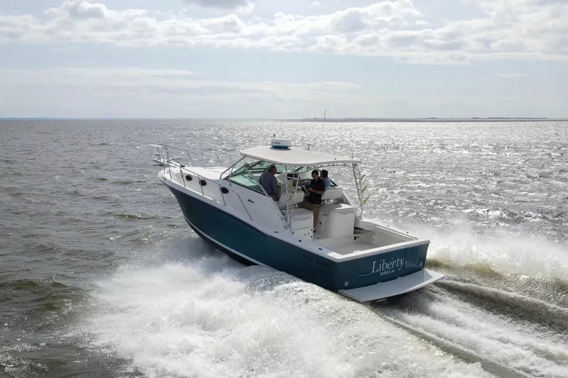 Slide: The Image of 2004 Wellcraft 330 Coastal boat cruising on open water under a cloudy sky. - 11