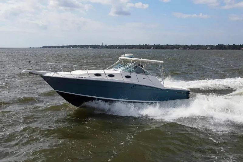 Slide: The Image of 2004 Wellcraft 330 Coastal boat cruising on open water under a partly cloudy sky. - 12