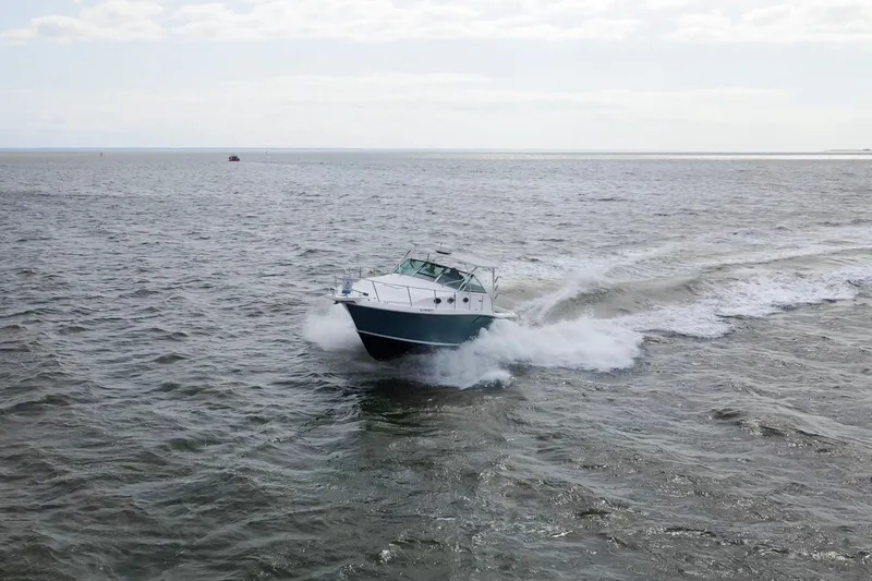 Slide: The Image of 2004 Wellcraft 330 Coastal boat cruising on open water, creating waves. - 13