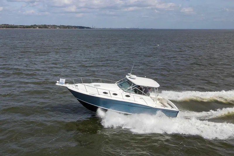 Slide: The Image of 2004 Wellcraft 330 Coastal boat cruising on open water under a cloudy sky. - 14