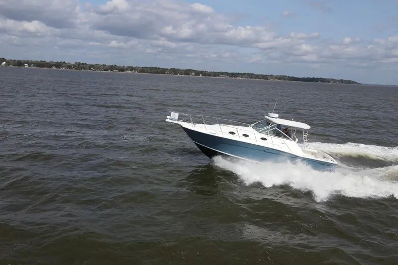 Slide: The Image of 2004 Wellcraft 330 Coastal boat cruising on open water under a cloudy sky. - 15