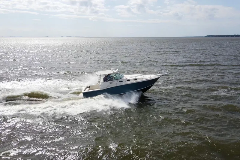 Slide: The Image of 2004 Wellcraft 330 Coastal boat cruising on open water under a cloudy sky. - 16