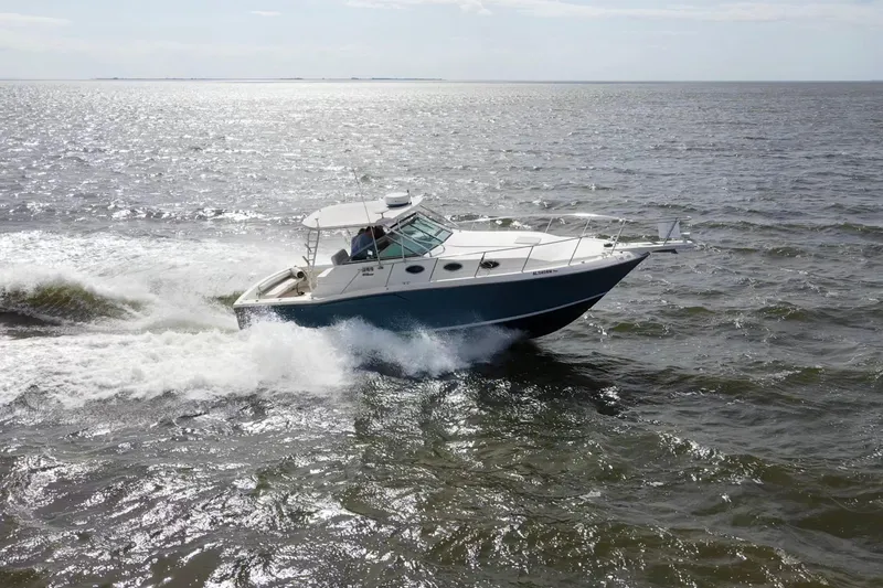 Slide: The Image of 2004 Wellcraft 330 Coastal boat cruising on open water, creating waves. - 17