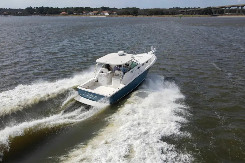 Slide: The Image of 2004 Wellcraft 330 Coastal boat cruising on open water, creating a wake. - 18