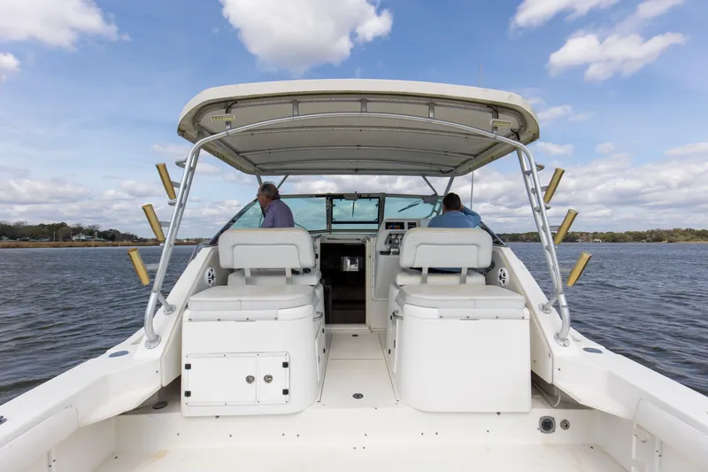 Slide: The Image of 2004 Wellcraft 330 Coastal boat on water, featuring dual seats and fishing rod holders. - 24
