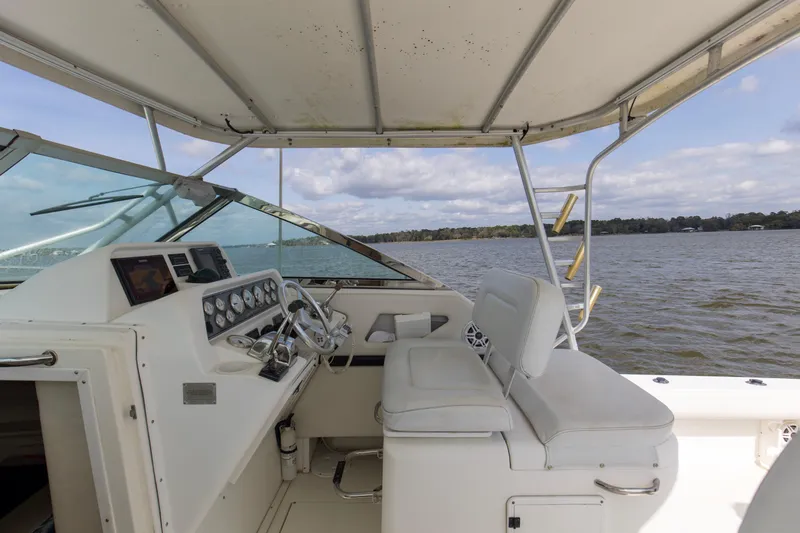 Slide: The Image of 2004 Wellcraft 330 Coastal boat interior with helm, steering wheel, and seating on a lake. - 28