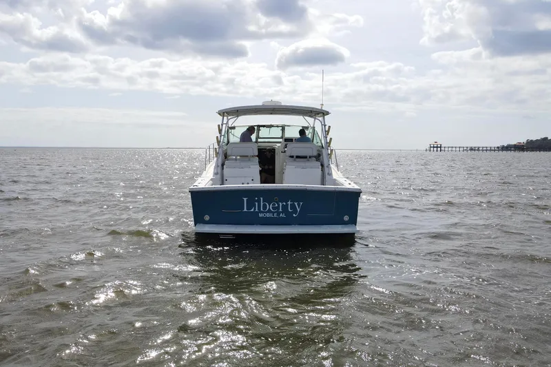Slide: The Image of 2004 Wellcraft 330 Coastal boat named "Liberty" on open water under cloudy sky. - 3