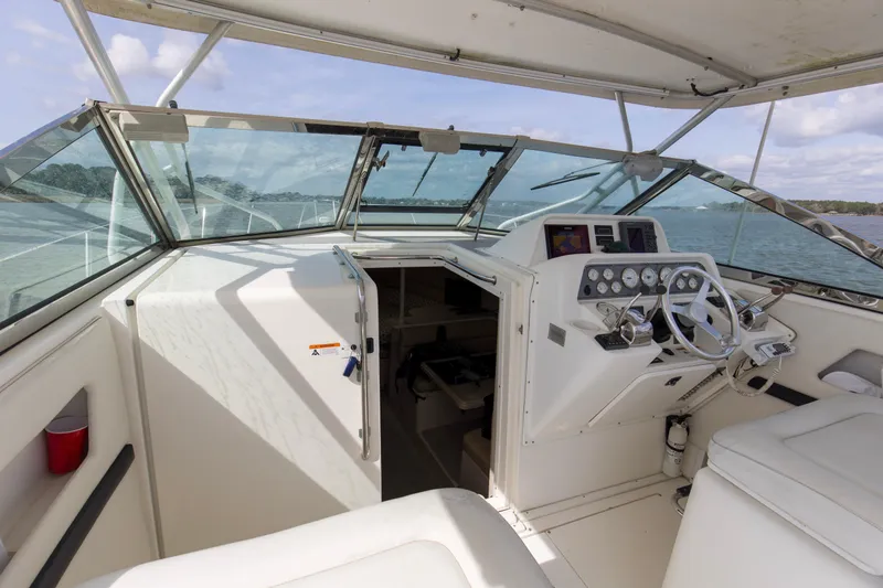 Slide: The Image of 2004 Wellcraft 330 Coastal boat cockpit with steering wheel and control panel on open water. - 30