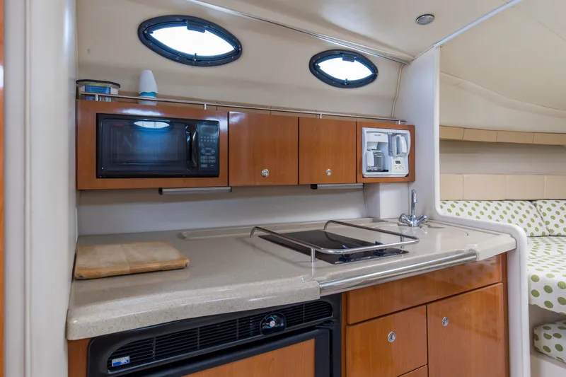 Slide: The Image of 2004 Wellcraft 330 Coastal boat interior kitchen with microwave, stove, and sink. - 34