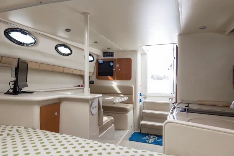 Slide: The Image of Interior of 2004 Wellcraft 330 Coastal boat, featuring seating, table, and portholes. - 36