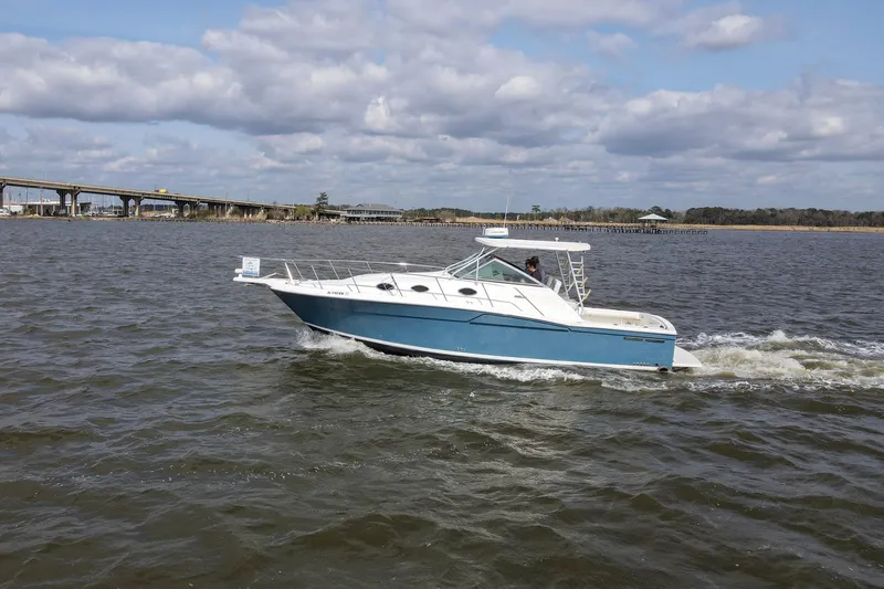 Slide: The Image of 2004 Wellcraft 330 Coastal boat cruising on a river under a cloudy sky. - 37