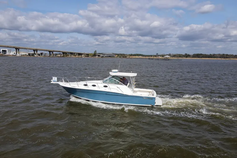 Slide: The Image of 2004 Wellcraft 330 Coastal boat cruising on a river under a cloudy sky. - 5