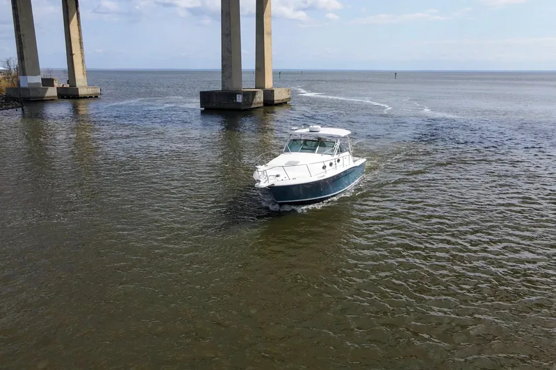 Slide: The Image of 2004 Wellcraft 330 Coastal boat cruising under a bridge on a sunny day. - 8