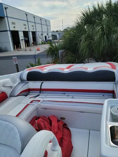 Slide: The Image of Interior of a 2000 Baja 442 boat with red and white seating near a warehouse. - 15