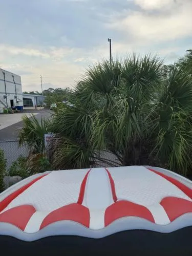 Slide: The Image of Baja 442 boat (2000) with red and white upholstery, near palm trees and industrial buildings. - 16