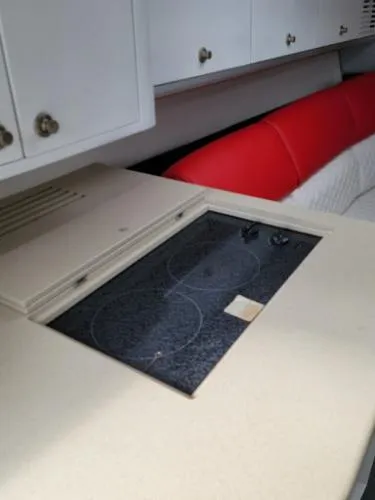 Slide: The Image of Interior of a 2000 Baja 442 boat featuring a compact kitchen with a stovetop. - 9