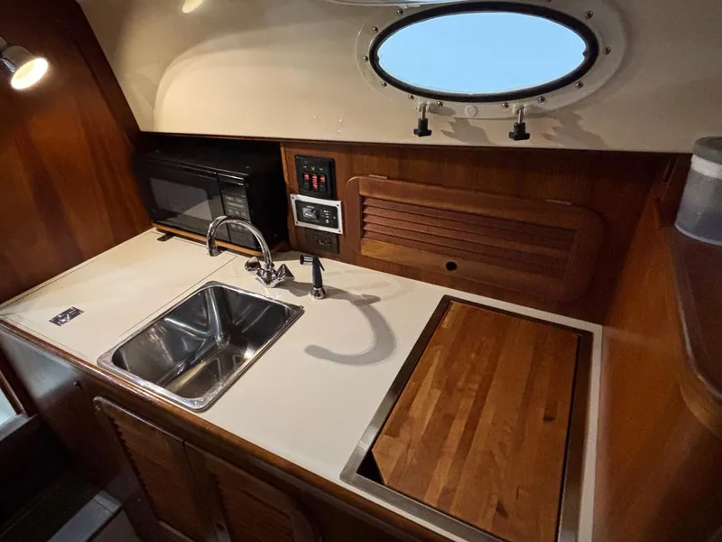 Slide: The Image of Compact galley in 2002 Hinckley Picnic Boat 36 with sink, cutting board, and porthole window. - 11