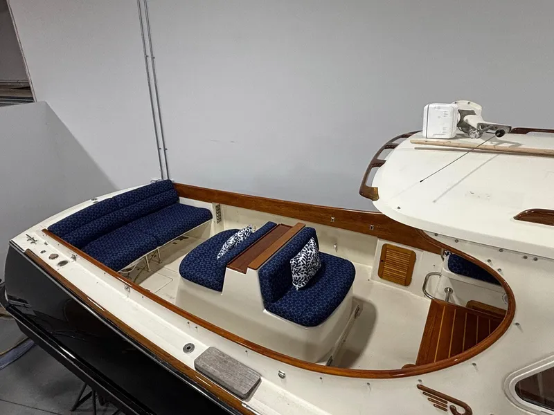 Slide: The Image of 2002 Hinckley Picnic Boat 36 with blue seating and wooden accents in a showroom. - 4