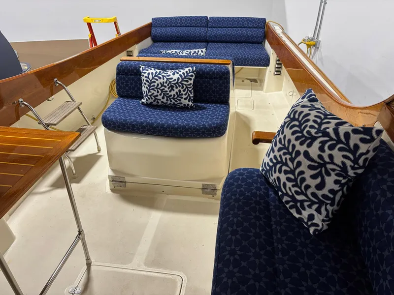 Slide: The Image of 2002 Hinckley Picnic Boat 36 interior with blue patterned cushions and wooden accents. - 5