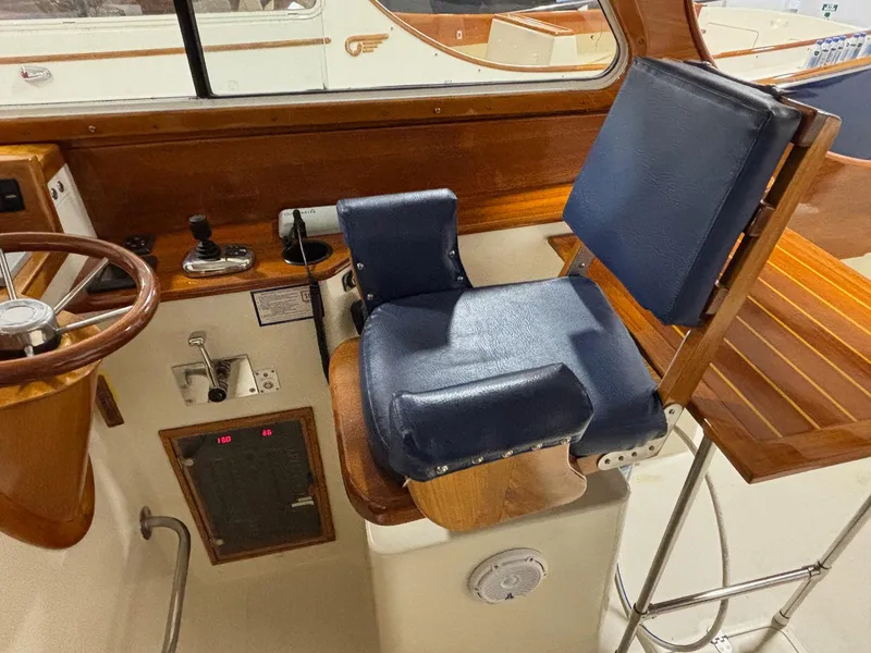 Slide: The Image of Helm station of 2002 Hinckley Picnic Boat 36 with blue seat and wooden accents. - 9