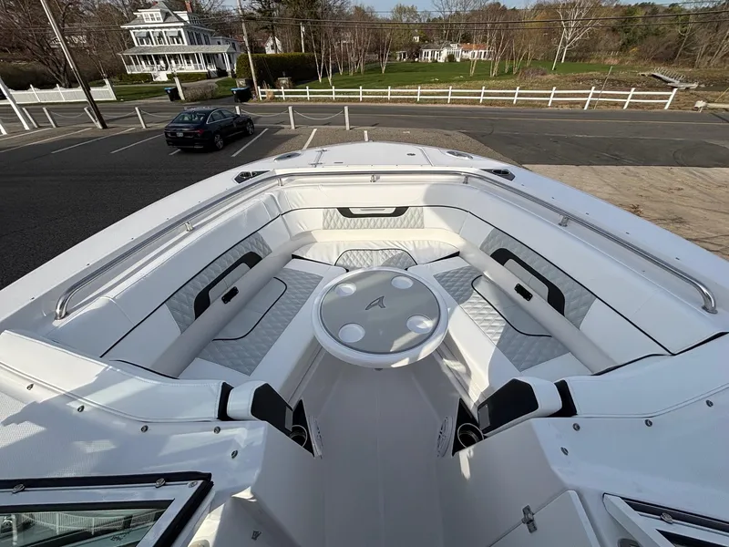 Slide: The Image of 2025 Blackfin 272 DC boat interior with spacious seating and table, parked near a road. - 10