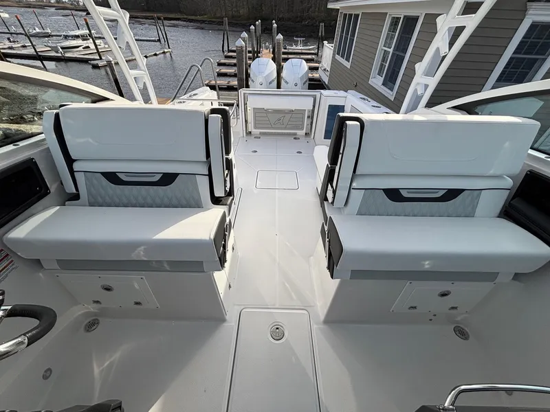 Slide: The Image of 2025 Blackfin 272 DC boat interior with dual seating, docked by a waterfront house. - 16