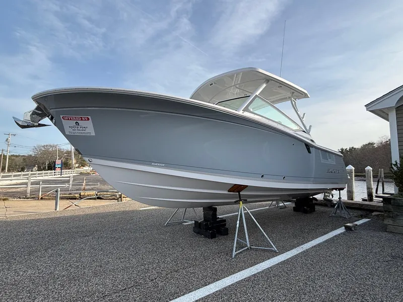 Slide: The Image of 2025 Blackfin 272 DC boat on stands, displayed outdoors under a clear sky. - 2