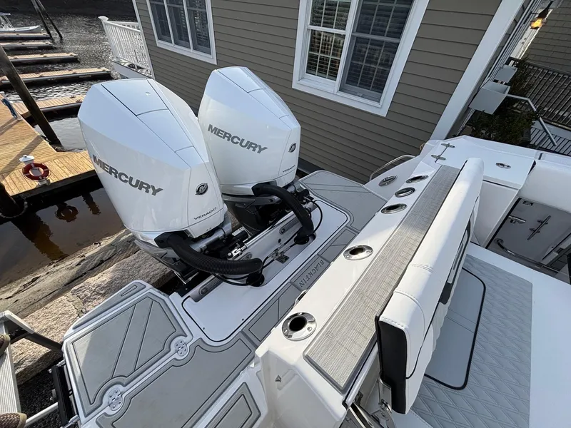 Slide: The Image of 2025 Blackfin 272 DC boat with dual Mercury outboard engines, docked near a house. - 26