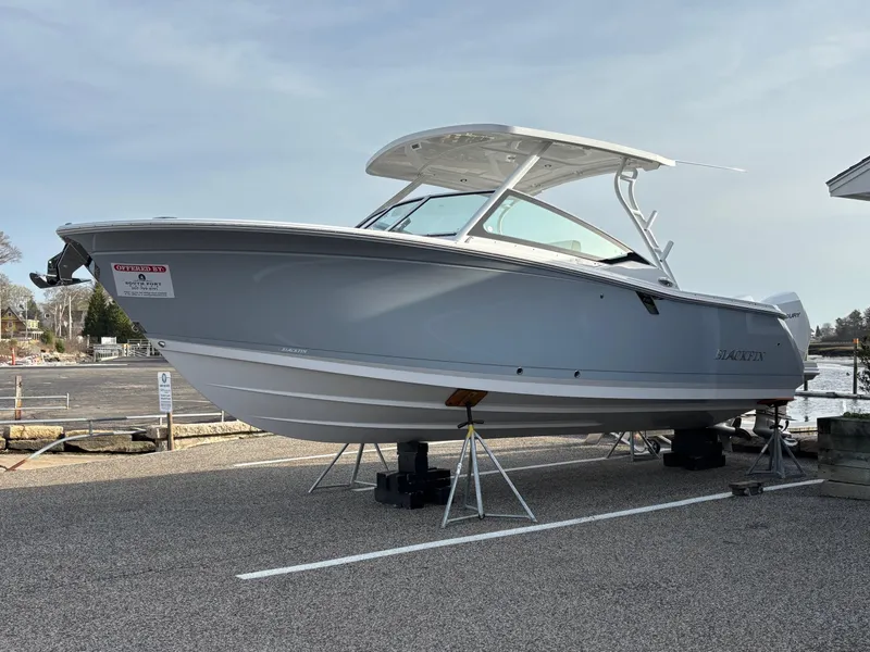 Slide: The Image of 2025 Blackfin 272 DC boat on display, elevated on stands, in a marina setting. - 3