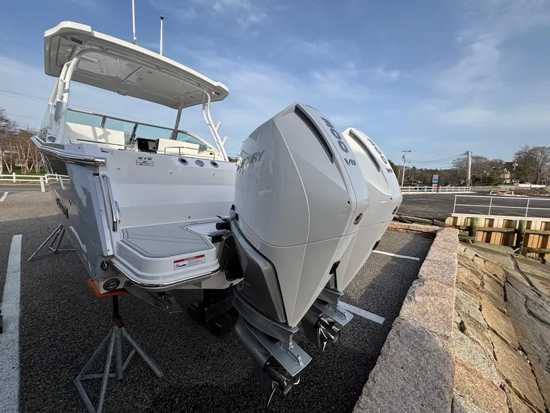 Slide: The Image of 2025 Blackfin 272 DC boat with dual outboard engines on display in a parking area. - 7