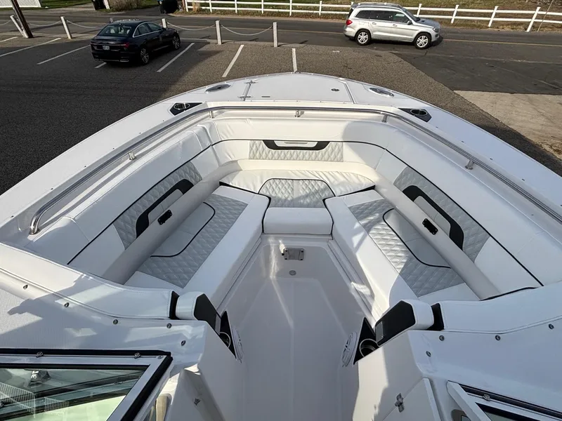Slide: The Image of 2025 Blackfin 272 DC boat interior with white cushioned seating in a parking lot. - 9