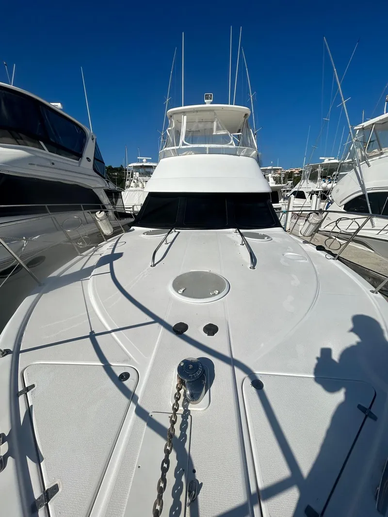 Slide: The Image of 2004 Riviera 40 yacht docked, showcasing sleek design and spacious deck under clear blue sky. - 16