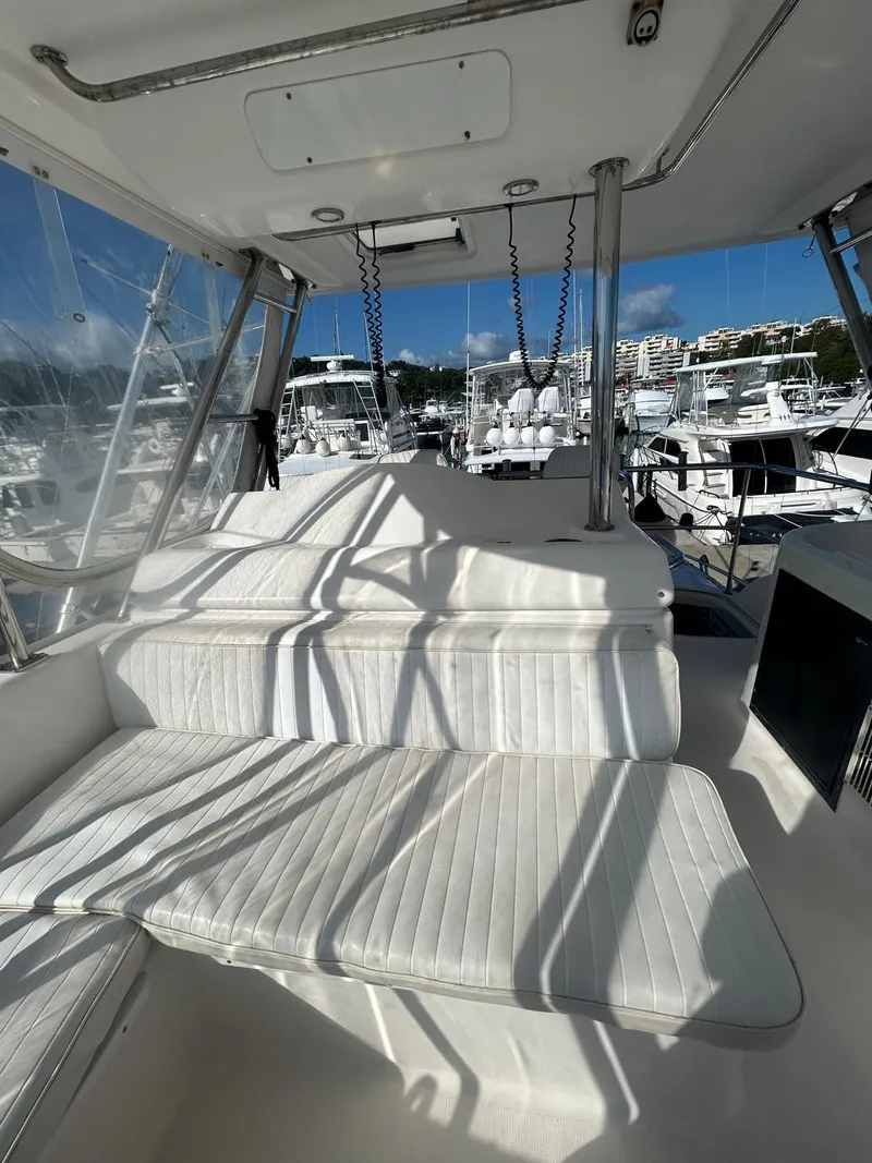 Slide: The Image of 2004 Riviera 40 yacht interior with white seating, docked at a marina under clear skies. - 8