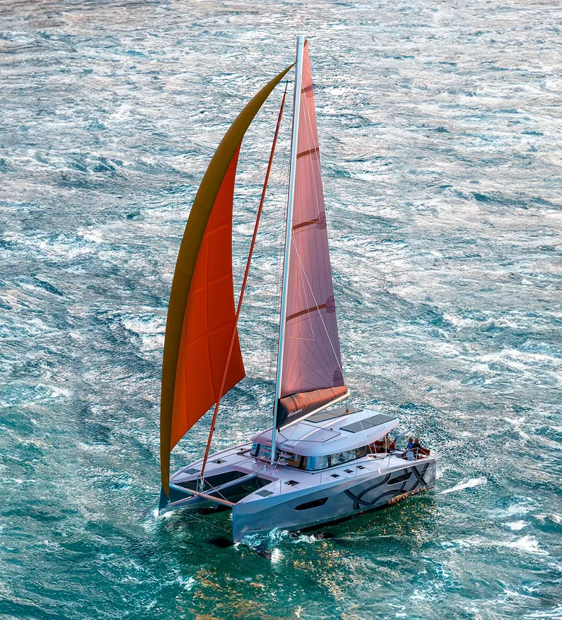 Slide: The Image of 2025 Excess 13 catamaran sailing on open water with vibrant sails. - 1