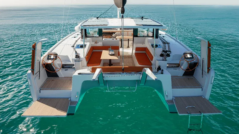 Slide: The Image of 2025 Excess 13 catamaran on turquoise water, featuring spacious deck and modern design. - 2