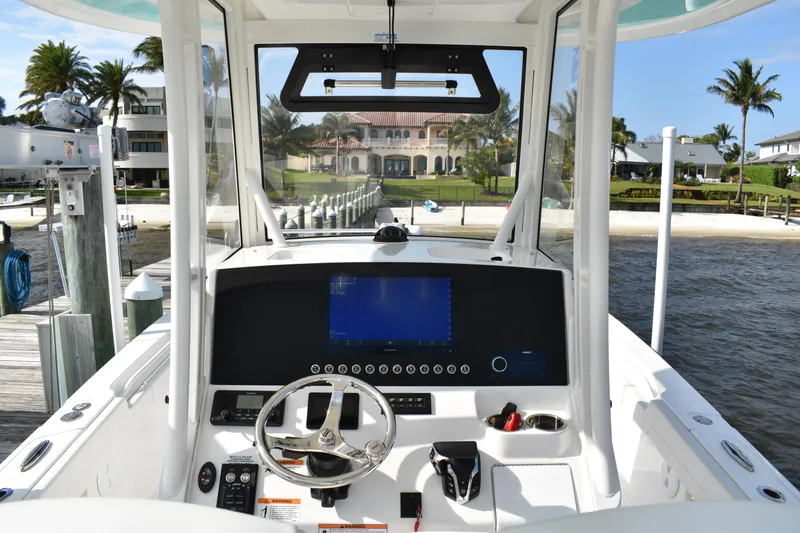 Slide: The Image of 2024 Regulator 26XO boat helm with modern controls, docked near a waterfront property. - 17