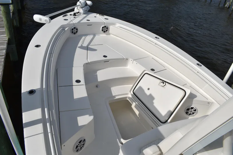 Slide: The Image of 2024 Regulator 26XO boat deck with open storage compartment, white seating, and speakers. - 25