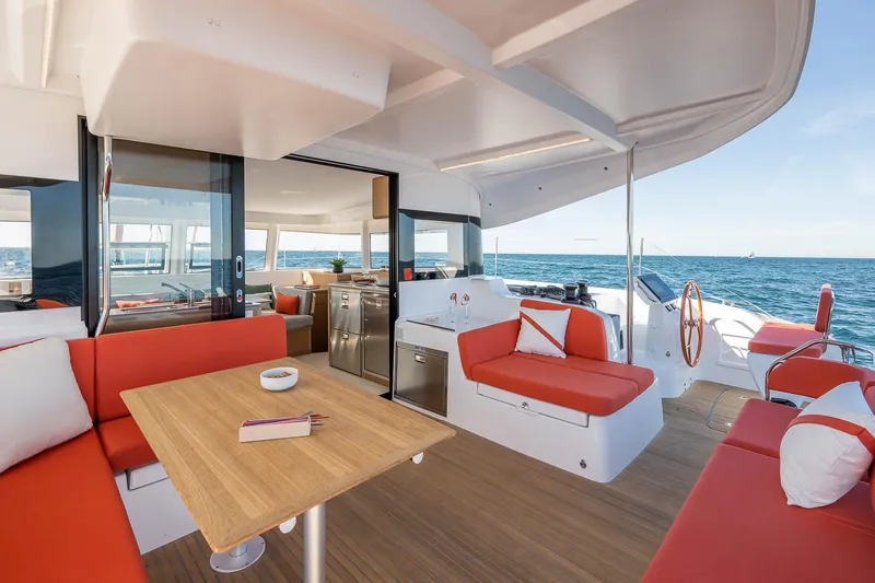 Slide: The Image of Luxurious 2025 Excess 14 catamaran interior with red seating, wooden table, and ocean view. - 10