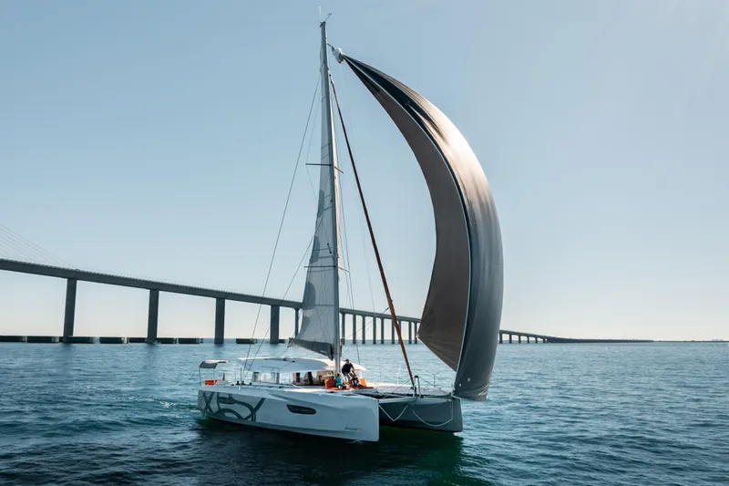 Slide: The Image of Sailing catamaran Excess 14, 2025 model, gliding near a bridge on a sunny day. - 4