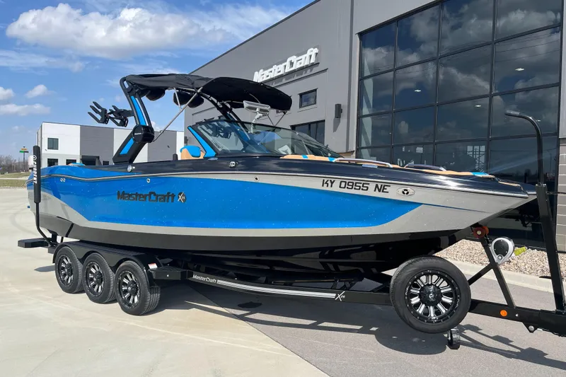 Slide: The Image of 2022 MasterCraft X26 boat in blue, parked on a trailer outside a dealership. - 1