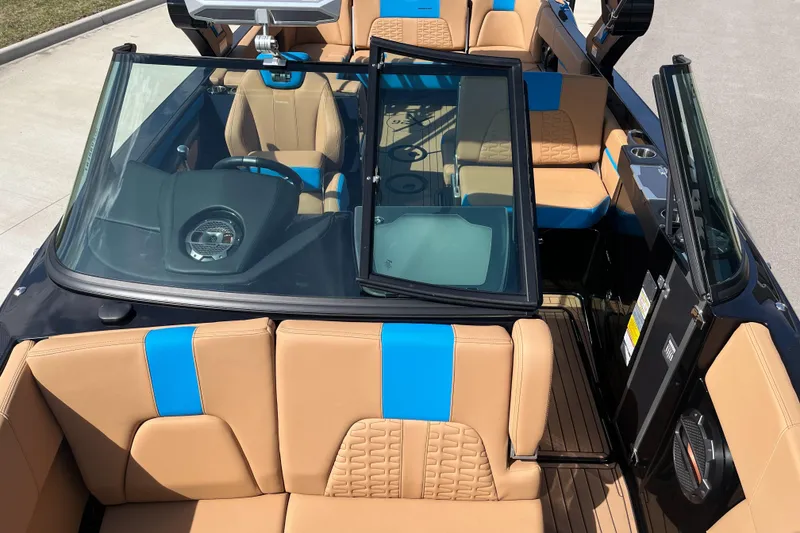Slide: The Image of 2022 MasterCraft X26 boat interior with tan and blue seating, modern dashboard, and open windshield. - 14