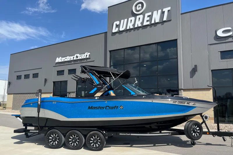 Slide: The Image of 2022 MasterCraft X26 boat in blue, parked outside a dealership with "Current" signage. - 2